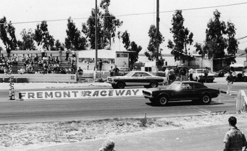 1967 Ford Fairlane - Two muscle cars compete at Fremont Raceway, with spectators watching from the stands.