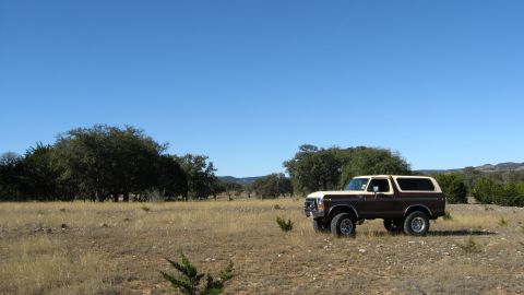 1979 Ford Bronco - A brown and white 1979 Ford Bronco sits in a dry, grassy landscape under a bright blue sky.