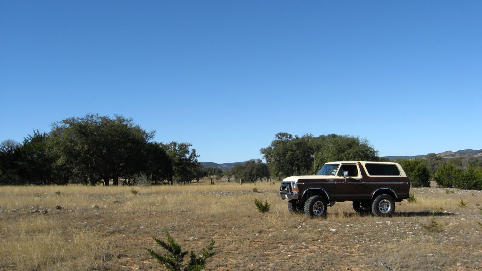 Brown and white 1979 Ford Bronco parked in a field
