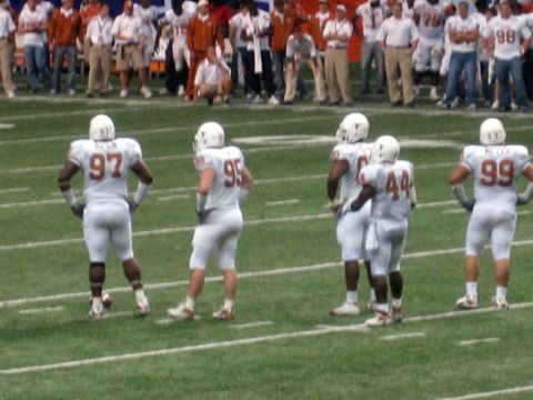 1986 Ford Bronco - Players in white uniforms stand on a football field, with numbers visible on their jerseys.