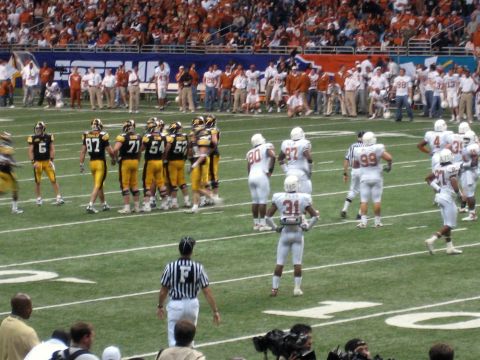 1986 Ford Bronco - Players and officials on a football field during a game, with a large crowd in the background.