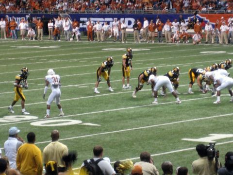 1986 Ford Bronco - Players in white and yellow uniforms face off on a football field during a game.