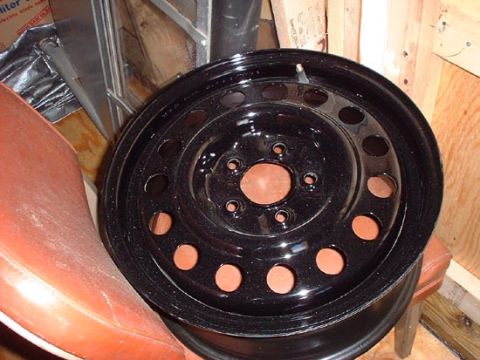 1997 Ford Crown Victoria - A black steel wheel is shown, likely a spare or replacement part, with visible cutouts for weight reduction and brake cooling.