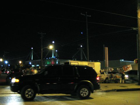 1986 Ford Bronco - A black SUV is seen driving on a street at night, with a building and lights in the background.