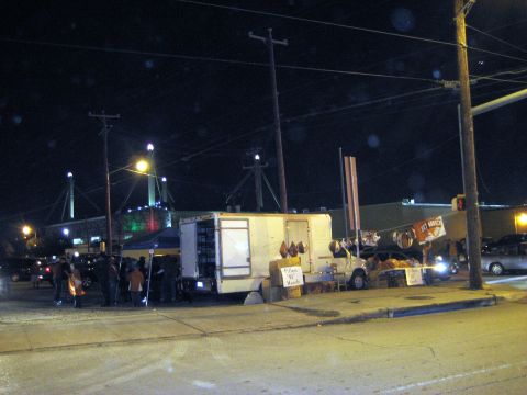 1986 Ford Bronco - A food truck is parked on the side of the road at night, with people gathered around it.