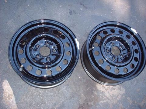 1997 Ford Crown Victoria - A pair of black steel wheels are shown, likely for a vehicle, against a grey, speckled background.