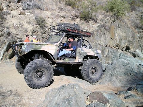 1993 Ford Bronco - A heavily modified 1993 Ford Bronco navigates a rocky trail with two passengers visible.