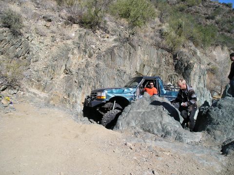 1993 Ford Bronco - A teal Ford F-150 navigates a narrow, rocky passage during an off-road excursion.