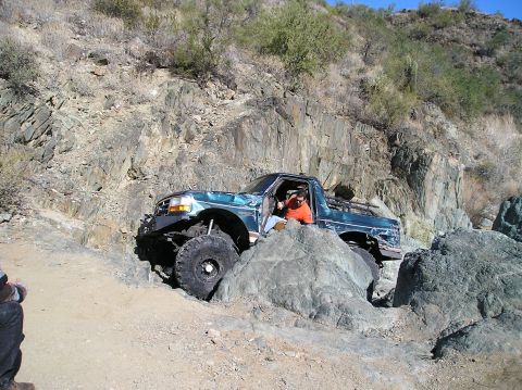 1993 Ford Bronco - Modified 1993 Ford Bronco tackling a challenging rocky obstacle on an off-road trail.