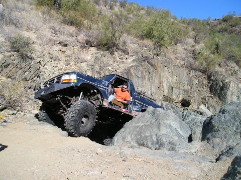 1993 Ford Bronco - This modified truck is tackling a challenging off-road course with large rocks and steep inclines.