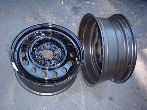1997 Ford Crown Victoria - Two steel wheels are shown, one with a chrome hubcap, resting on a concrete surface.