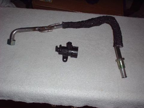 1997 Ford Crown Victoria - Close-up of an automotive part, likely a fuel line or vacuum hose with a sensor connector.
