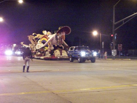 1990 Ford Bronco - A blue Ford Bronco is seen at night, towing a large, elaborate parade float.