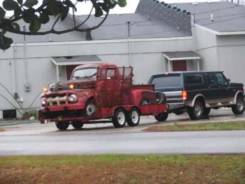 1952 Ford Pickup - A rusty red 1951 Ford pickup truck is transported on a trailer behind a dark SUV.
