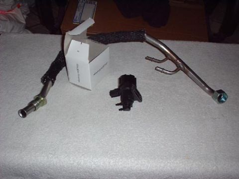 1997 Ford Crown Victoria - A fuel line and a sensor are laid out on a textured surface next to a small white box.