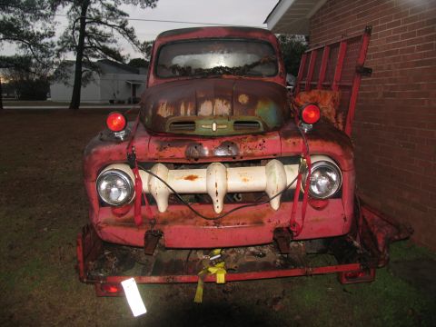 1952 Ford Pickup - This heavily rusted pickup truck features a distinctive white grille and red emergency lights.