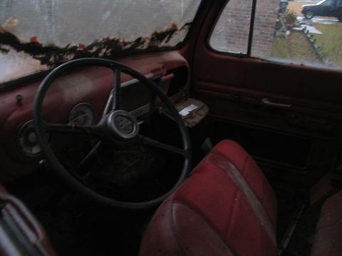1952 Ford Pickup - The interior of a red pickup truck, likely from the late 1940s, shows a worn steering wheel and seats.