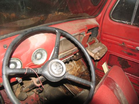 1952 Ford Pickup - The interior of a red 1952 Ford Pickup shows its dashboard, steering wheel, and seats, indicating a vintage vehicle.