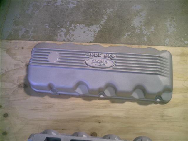 Silver Ford valve cover with ribbed texture and oval Ford logo