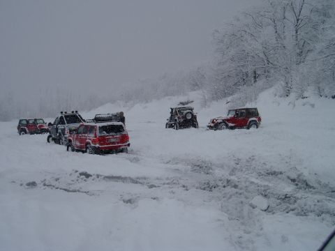 2000 Ford E350 - Multiple Jeeps navigate a snowy terrain, with some vehicles appearing stuck in the deep snow.