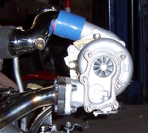 1988 Pontiac Fiero - Close-up of a turbocharger and exhaust manifold assembly, likely for an engine modification.