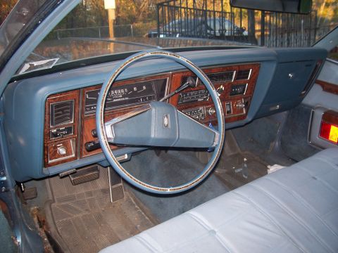 1999 Ford Crown Victoria - The interior of a car features a blue dashboard with wood grain accents and a prominent steering wheel, with a Supermotors.net watermark in…