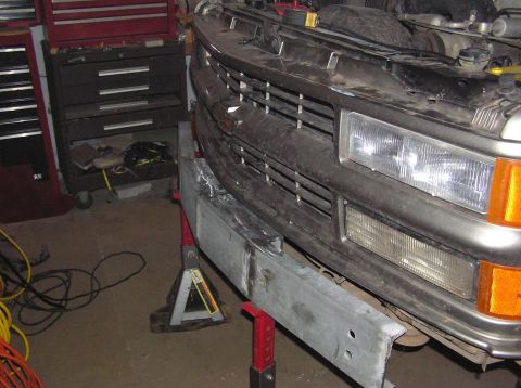 2000 Chevrolet Tahoe - Front bumper repair in progress on a 1990s Chevrolet truck, supported by jack stands in a garage.