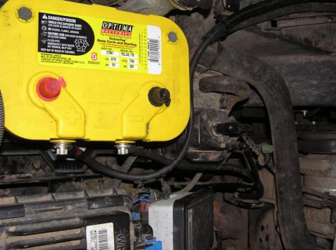 2000 Chevrolet Tahoe - Close-up of an Optima YellowTop battery and surrounding engine bay components.