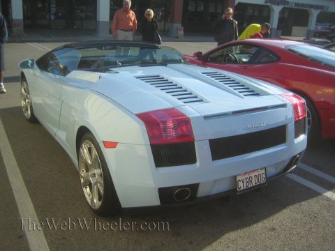1985 Ford Mustang - A light blue Lamborghini Gallardo Spyder is parked next to a red Ferrari at a car show.