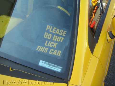 1985 Ford Mustang - A humorous sticker on the windshield of a yellow car reads "PLEASE DO NOT LICK THIS CAR".