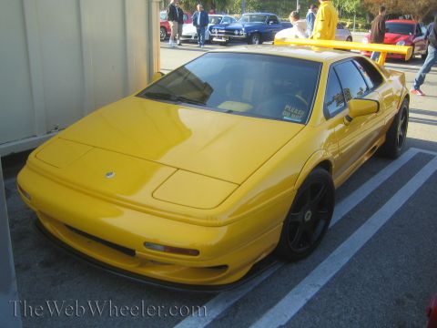 1985 Ford Mustang - Yellow Lotus Esprit with a large rear spoiler and a 'PLEASE DO NOT' sticker on the windshield.