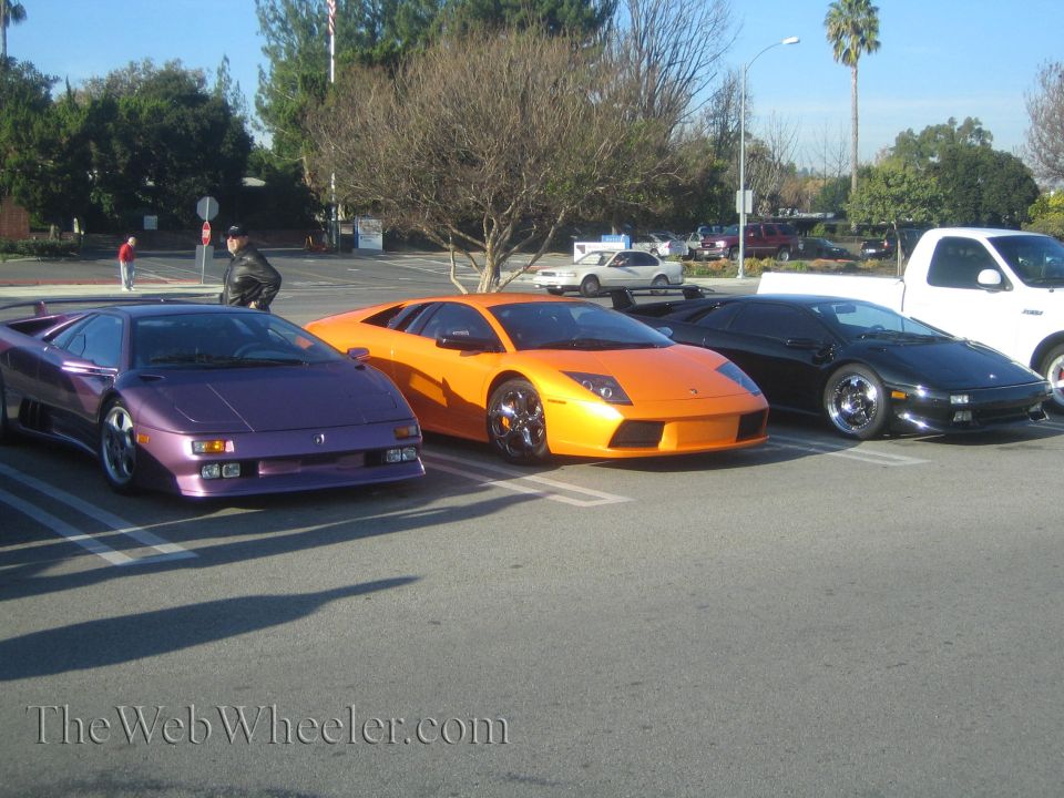 Purple, orange, and black Lamborghinis parked in a lot