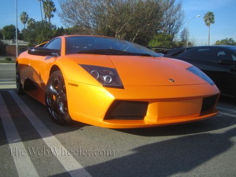 1985 Ford Mustang - An orange Lamborghini Murcielago is parked next to a black car at a car show.