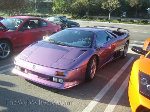 1985 Ford Mustang - A purple Lamborghini Diablo is parked at a car show next to other exotic vehicles.