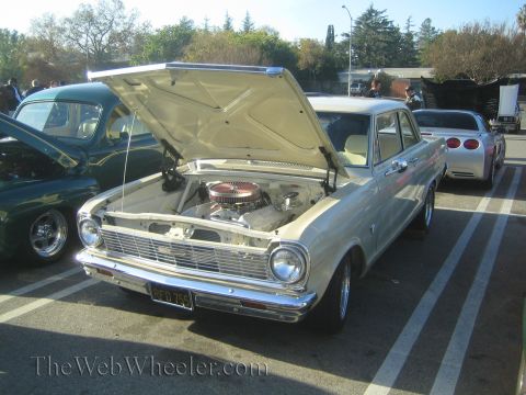 1985 Ford Mustang - Cream 1964 Chevrolet Nova at a car show, engine exposed. Other vehicles visible in background.