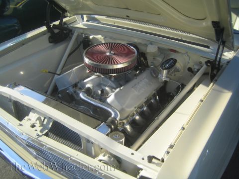 1985 Ford Mustang - The engine compartment of a classic car is shown with its hood open, revealing the V8 engine and its components.