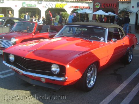 1985 Ford Mustang - Red 1969 Camaro convertible and a red Mini Cooper at a car show.