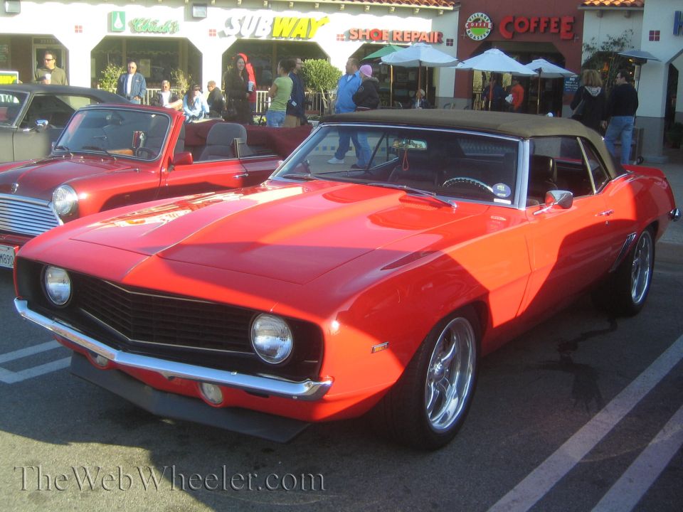 Red 1969 Chevrolet Camaro convertible parked next to a red Mini Cooper