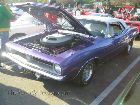 1985 Ford Mustang - A purple 1970 Plymouth Barracuda convertible is displayed with its hood open at a car show.