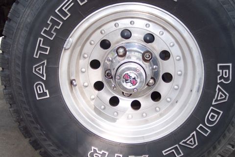 1996 Ford Bronco - This image shows a close-up of a vehicle's wheel, a tire with 'PATHFINDER' text and a chrome hub with a '4x4 AUTOMATIC' emblem.
