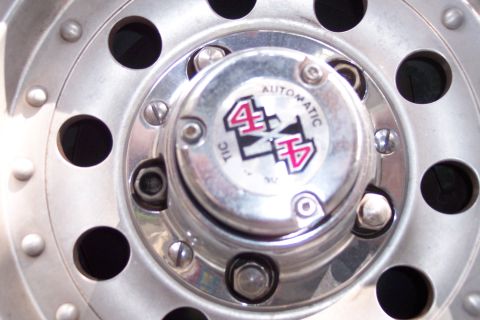 1996 Ford Bronco - Close-up of a chrome hubcap with a 4x4 emblem, indicating it is part of a vehicle's wheel assembly.