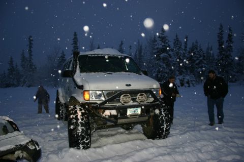 2003 Jeep TJ - A modified van sits in the snow during a winter storm, with two people standing nearby.