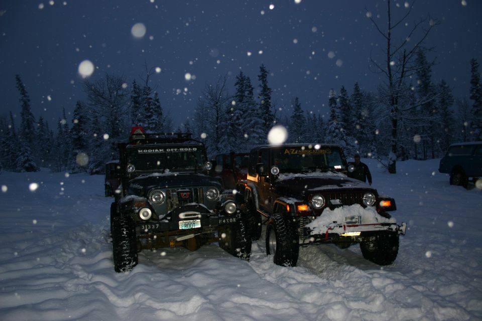 Two 2003 Jeep TJs in snow, one dark green, one maroon, with snow on windshields and hoods