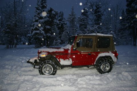 2003 Jeep TJ - A red Jeep Wrangler is parked in a snowy forest during a snowfall.