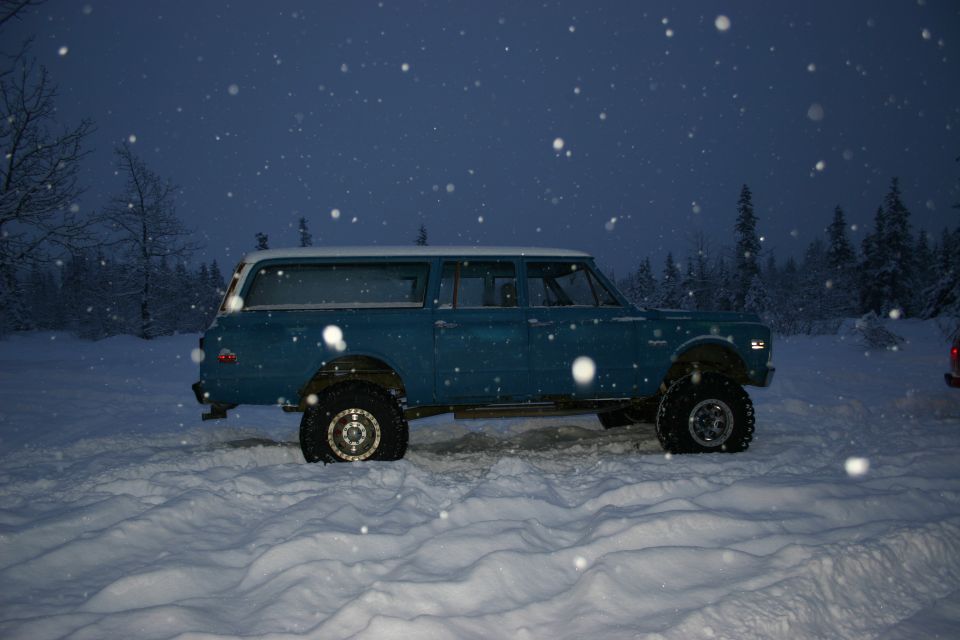 Blue station wagon with white roof parked in snow, side view
