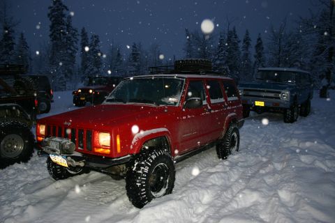 2003 Jeep TJ - Several 4x4 vehicles parked in a snowy forest during snowfall.
