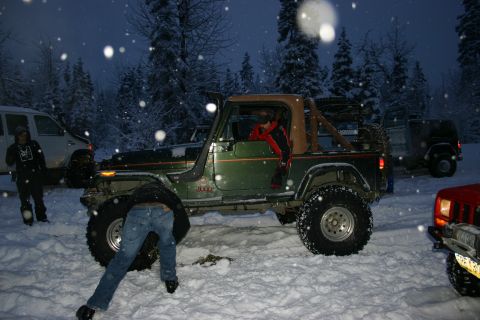 2003 Jeep TJ - A group of Jeeps are parked in the snow, with one person working on a vehicle.