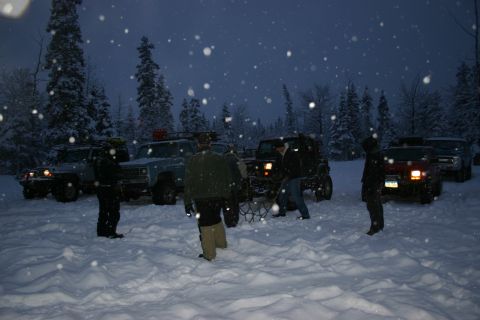 2003 Jeep TJ - Multiple Jeeps and other vehicles gathered in a snowy forest during snowfall.