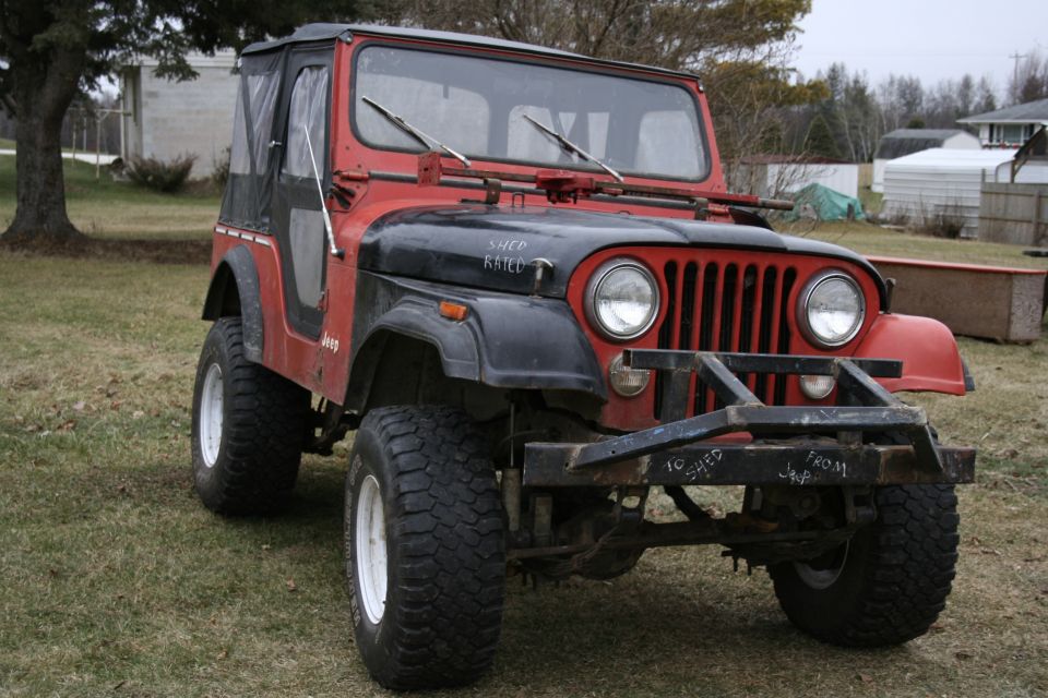 Red Jeep CJ with black hood, soft top and mud tires, hand-lettered SHED RATED on hood