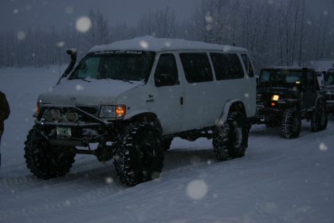 2003 Jeep TJ - Two modified off-road vehicles navigate a snowy landscape during snowfall.